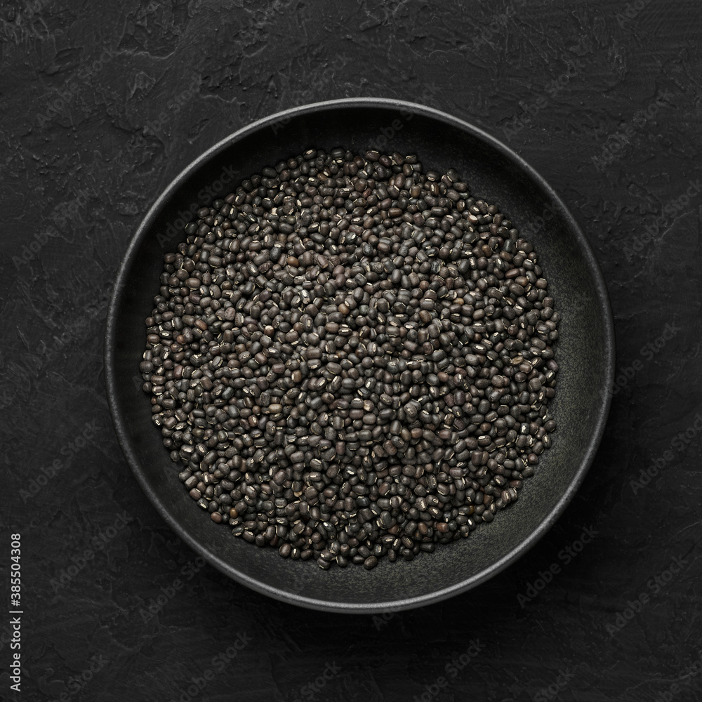 Black Gram or Urad Beans or Mung Beans in bowl on dark slate table top. Vigna Mungo is popular indian cuisine food ingredient. Top view Black Gram or Urad Beans or Mung Beans in bowl on dark slate table top. Vigna Mungo is popular indian cuisine food ingredient. Top view