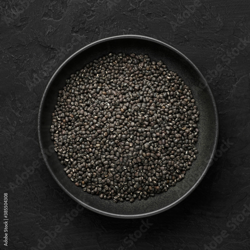 Black Gram or Urad Beans or Mung Beans in bowl on dark slate table top. Vigna Mungo is popular indian cuisine food ingredient. Top view