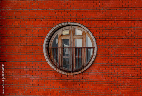 Vintage circle wooden window on a brick wall building. Architectural design with lines and circle
