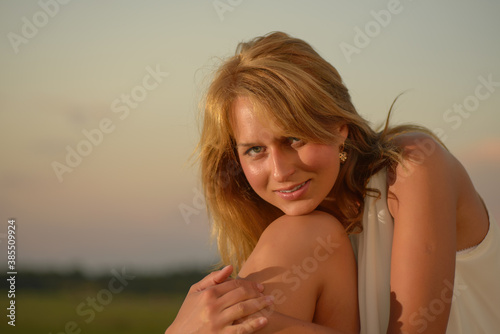 Blond woman posing at sunset time on a field