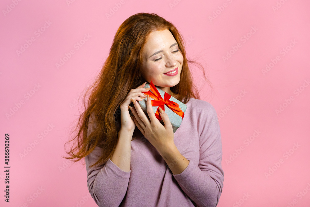 Excited woman received gift box with bow. She is happy and flattered by attention. Girl smiling with present on pink background. Studio portrait Excited woman received gift box with bow. She is happy and flattered by attention. Girl smiling with present on pink background. Studio portrait