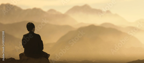 men sitting on top on mountain rock looks over mountain golden valley.