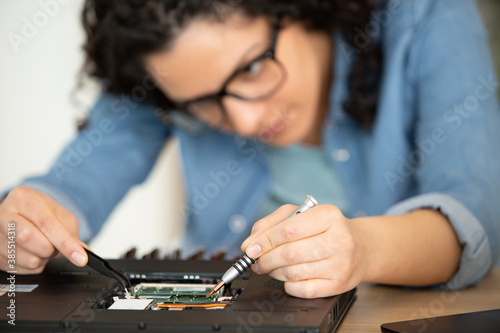 Photography female technician dismantling computer using tweezers