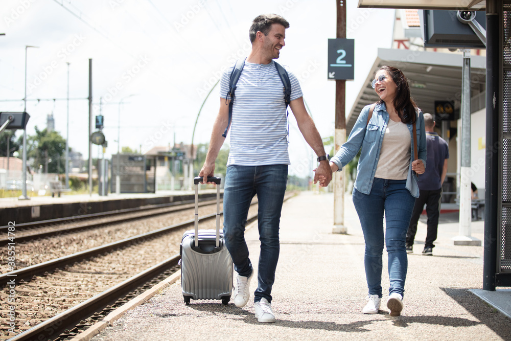 traveler couple backpacker tourist together at train station - obrazy, fototapety, plakaty 