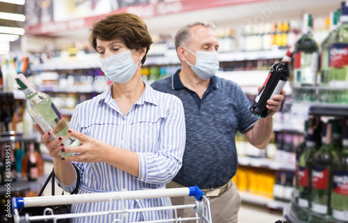 Pensioners in protective masks choose alcoholic beverages in supermarket