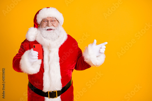 Excited santa claus with big belly use cellphone search x-mas magic fairy christmas eve discount ads point finger copyspace wear cap headwear belt isolated bright shine color background