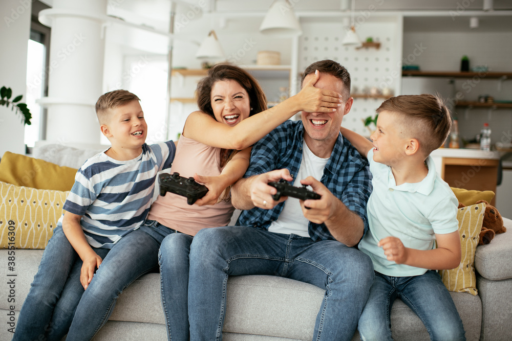 Husband and wife playing video games with joysticks in living room. Loving couple are playing video games with kids at home Husband and wife playing video games with joysticks in living room. Loving couple are playing video games with kids at home
