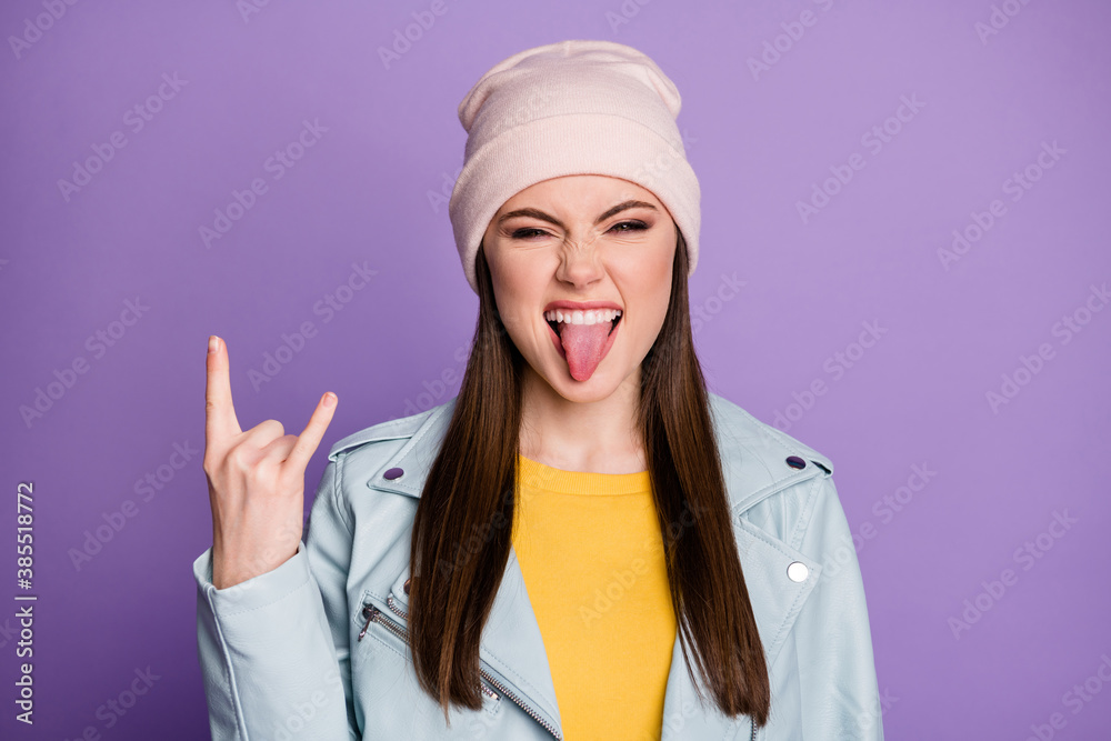 Closeup photo of good mood pretty lady sticking tongue out mouth teasing behavior crazy rocker showing horns wear casual hat blue modern jacket isolated purple color background Closeup photo of good mood pretty lady sticking tongue out mouth teasing behavior crazy rocker showing horns wear casual hat blue modern jacket isolated purple color background