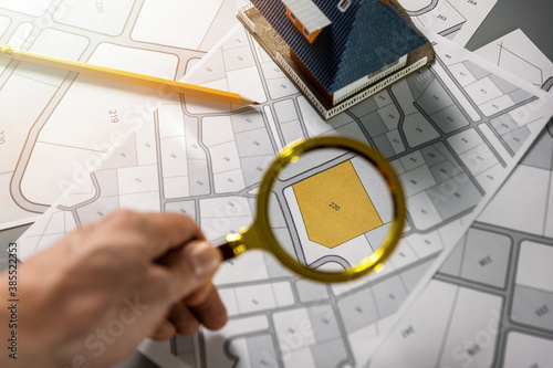 searching building plot for family house construction - hand with magnifier on cadastre map photo