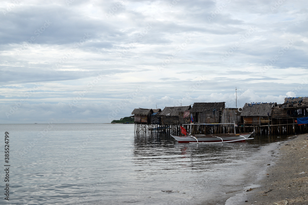 Small fishing boat anchored beside the over water stilt Bajau shanty houses Small fishing boat anchored beside the over water stilt Bajau shanty houses
