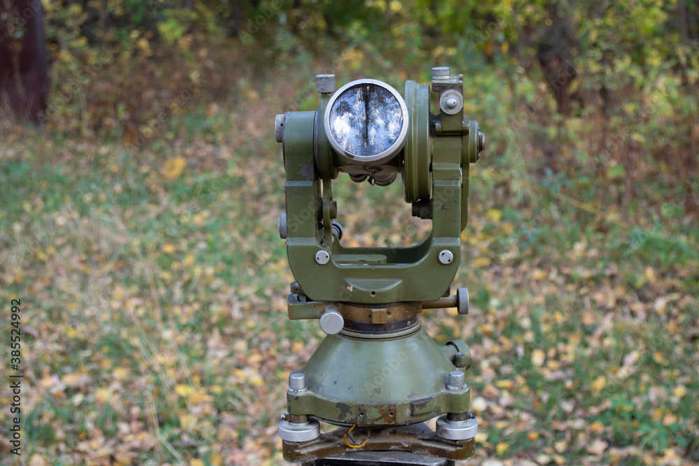 Old optical theodolite for geodetic works on the background of the forest. Old optical theodolite for geodetic works on the background of the forest.