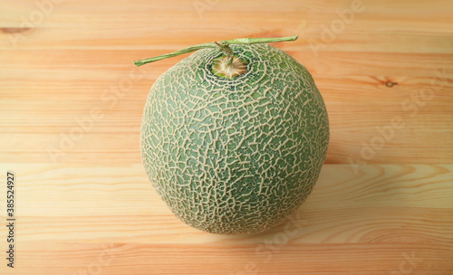 Fresh Ripe Muskmelon or Cantaloupe Melon Fruit with Stem Isolated on Wooden Table