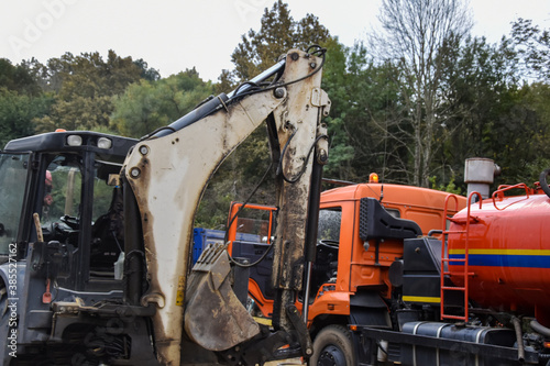 Truck and tractor, excavator at work on the site. Freight transport for road and bridge repair.