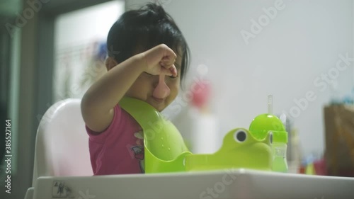 Adorable asian malay kid learning to eat cereal for the first time photo