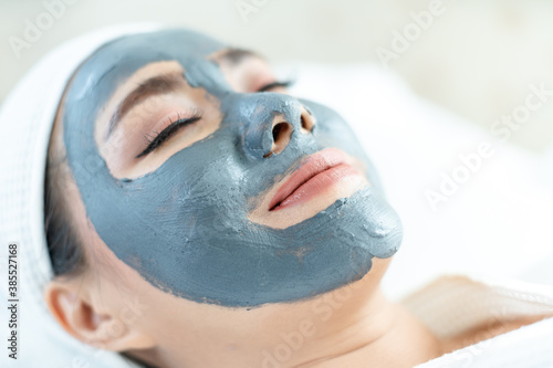 Beautiful woman masking skin in a facial spa shop.