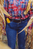 Crop view of Young woman farmer with corn harvest. Worker holding autumn corncobs. Farming and gardening