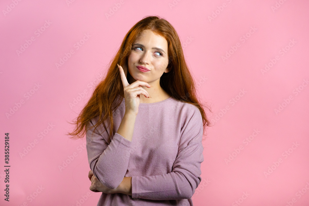 Thinking woman looking up and around on pink background. Happy smiling face expressions. Pretty model with attractive appearance Thinking woman looking up and around on pink background. Happy smiling face expressions. Pretty model with attractive appearance