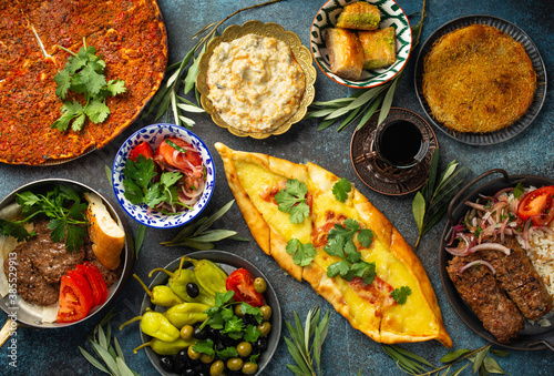 Traditional Turkish food, assorted dishes and mezze appetizers on rustic background from above. Pide, Lahmacun, meat kebab, Turkish meatballs, sweet baklava and Künefe. Middle East cuisine, top view photo