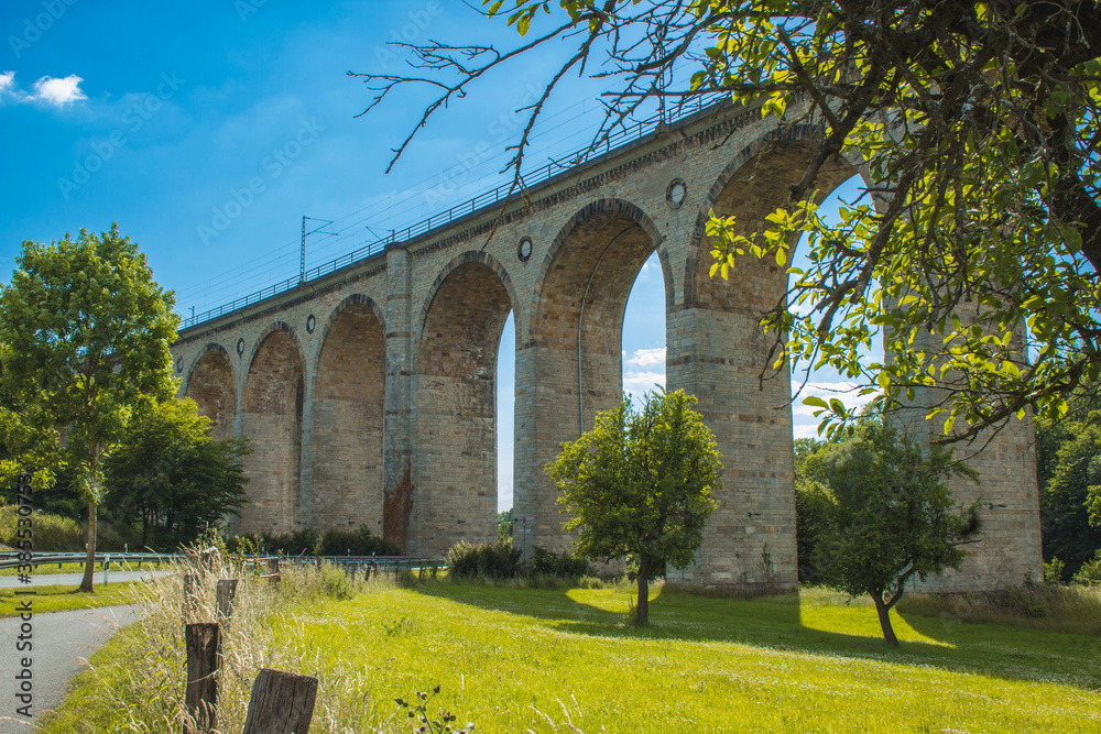 Fototapeta premium Train viaduct in Altenbeken, North Rhine Westphalia, Germany. Old stone railway surrounded by green park