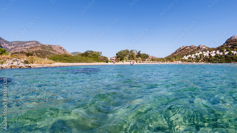 Obraz premium Clear turquoise water of Aegean sea and Caraincir beach. Beautiful Mediterranean seascape of ripple water with sunbeams reflections. Province of Mugla, Datca peninsula, Turkey