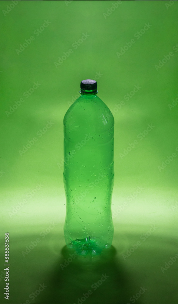 Green plastic water bottle on a green background. Concept for the packaging of drinks. Waste disposal. Side view Green plastic water bottle on a green background. Concept for the packaging of drinks. Waste disposal. Side view