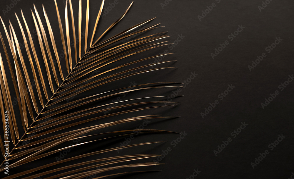 Fototapeta premium Closeup of golden palm leaves on black background. Copy space. Flat lay. Luxury invitation card template.