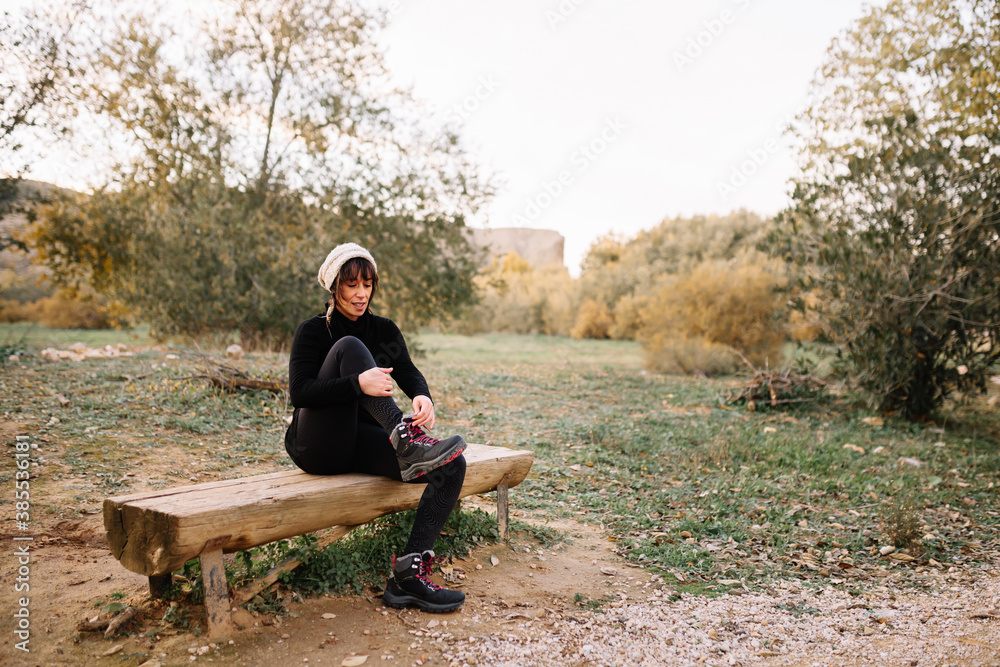 Fototapeta premium Woman hiker resting on the bench in park after trekking