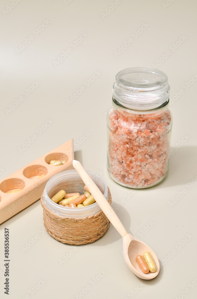 Fototapeta premium Herb in capsules in wooden bowl on pastel beige background. Beauty products for face and body skin care