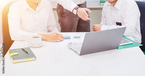 three excited young businessmen having a discussion in front of a laptop