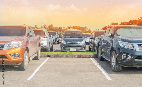 Car parked in asphalt parking lot and one empty space parking in nature with trees, beautiful cloudy sky and mountain background .Outdoor parking lot with fresh ozone and green environment