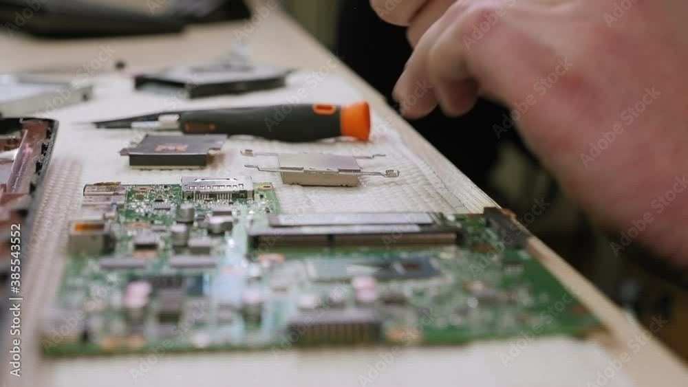 Repairman cleans laptop processor from old thermal paste. Service electronics and computers concept.