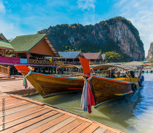 Traditional longtailed speed boats moored on the jetty of the settlement built on stilts of Ko Panyi in Phang Nga Bay, Thailand photo