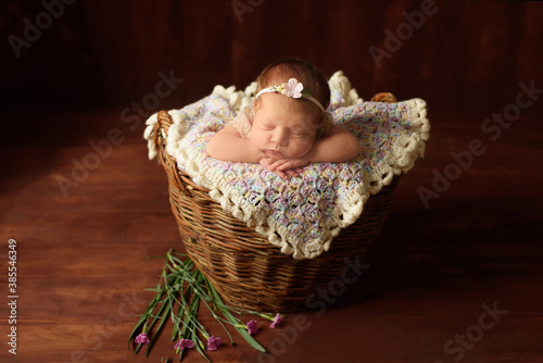Beautiful sleeping newborn girl sweetly fell asleep next to flowers