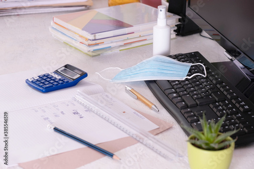 school items and a mask with antiseptic are lying on the desk