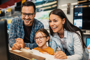 Happy family buying laptop in store.