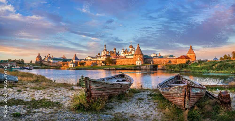 Fototapeta premium Old wooden boats on the shore and a view of the temples of the Solovetsky Monastery