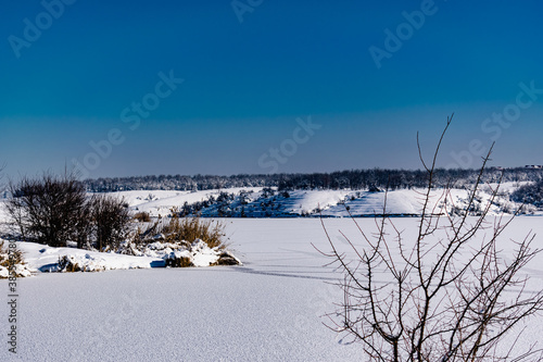 Spacious snow landscape. River and hills in Russia, white winter on the terrain, a lot of fluffy snow and ice under a beautiful blue sky. Rostov region, town of Shakhty, the river Grushevka 