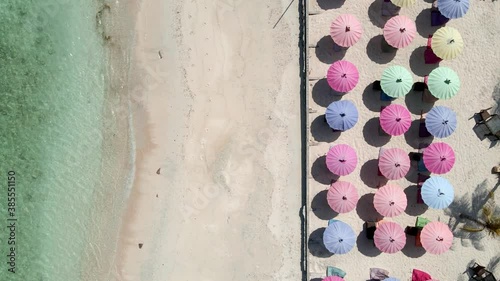 Beautiful clear sea water,sandy beach and multicolred sunshades during sunny day in Gili Trawangan. photo