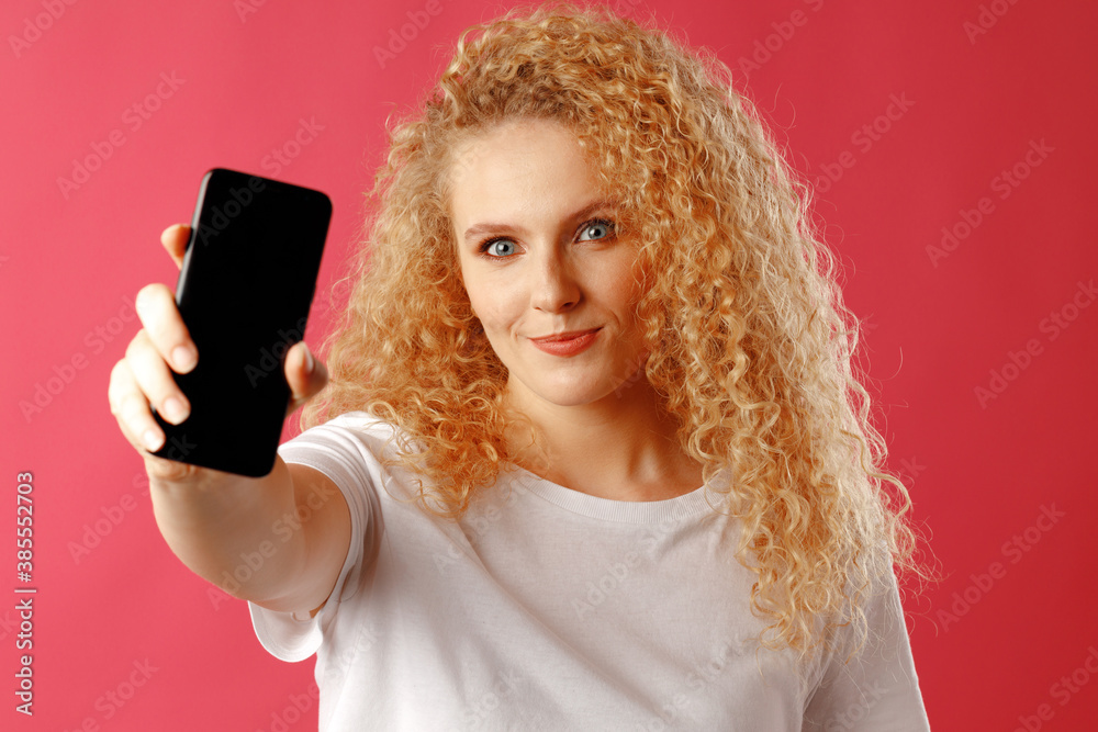 Blonde young woman showing black smartphone screen with copy space Blonde young woman showing black smartphone screen with copy space