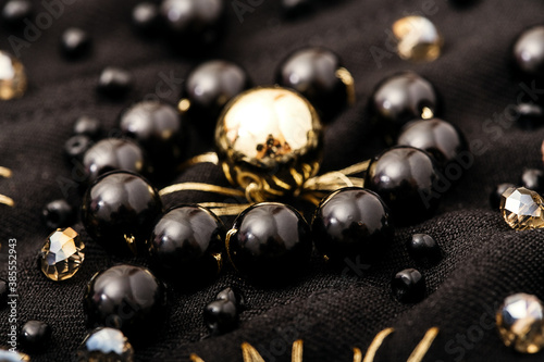 Macro flower of golden and black beads on black textile