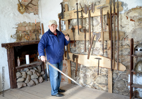 An elderly man holds a knight's sword in his hand. Shaaken Castle, XIII century. Kaliningrad region photo