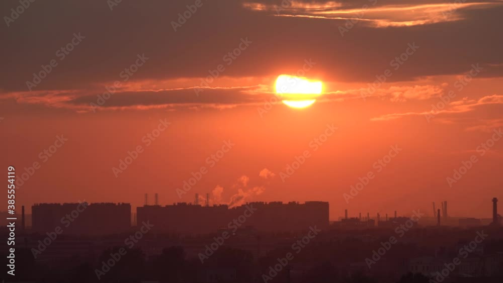 Sun comes down from behind a cloud and sets over the horizon against the backdrop of an industrial area. Smoke from the pipes, smog and haze from the heat. Sun comes down from behind a cloud and sets over the horizon against the backdrop of an industrial area. Smoke from the pipes, smog and haze from the heat.