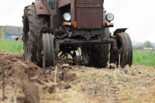 Old Soviet 4x4 wheeled brown tractor on the field front view close up, soil cultivation on an autumn day on grass background, countryside agriculture farming mechanization