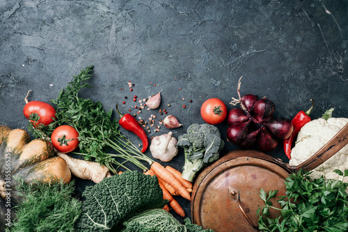 Vegetarian cooking ingredients. Autumn harvest fair. Healthy, clean food cooking and eating concept. Copper pan, colorful autumn vegetables, pumpkin on dark background. Top view. Copy space. photo