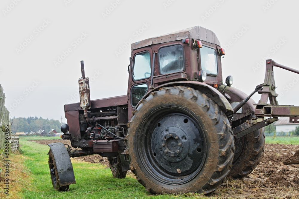 Old brown Soviet diesel wheeled tractor close up with on the field, soil cultivation on an autumn day, rural agriculture farming landscape Old brown Soviet diesel wheeled tractor close up with on the field, soil cultivation on an autumn day, rural agriculture farming landscape