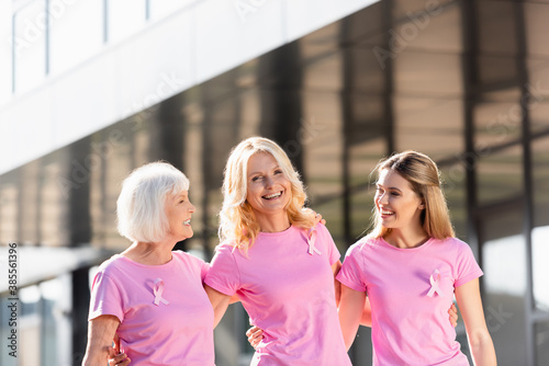 Selective focus of three women with ribbons of breast cancer awareness outdoors