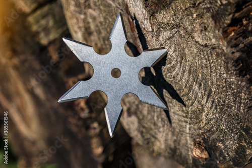 Shuriken (throwing star), traditional japanese ninja cold weapon stuck in wooden background