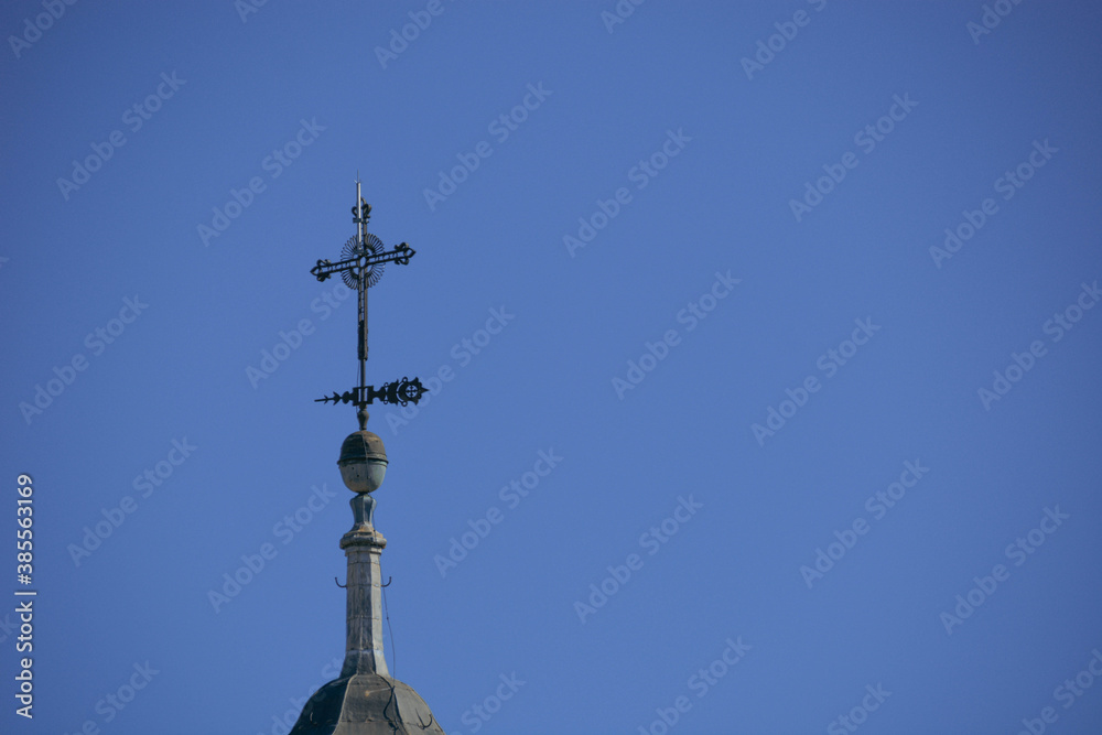 Detalle de cruz de un campanario de iglesia neoclásica con cielo azu