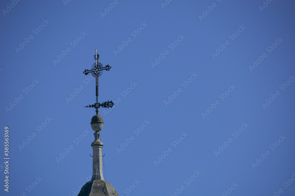 Detalle de cruz de un campanario de iglesia neoclásica con cielo azu Detalle de cruz de un campanario de iglesia neoclásica con cielo azu