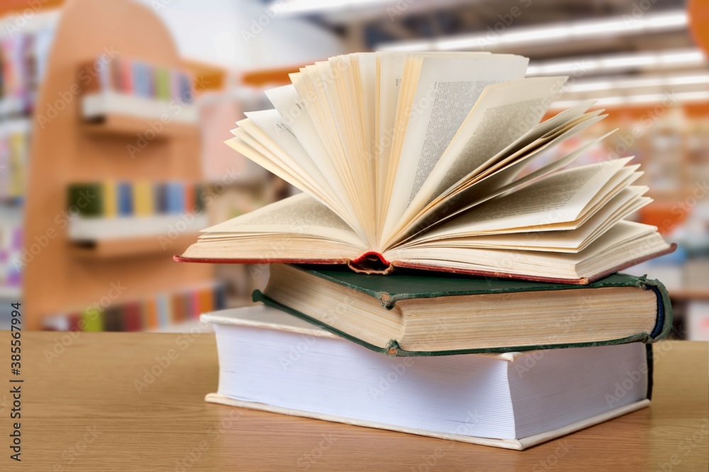 Open book on stack of books with library background. Open book on stack of books with library background.